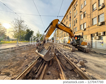 Excavator working on tram track dismantling. City infrastructure under construction. 127047780