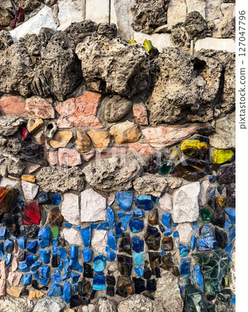 Colorful stone and glass mosaic embedded in textured concrete wall. The image explores craftsmanship and tactile urban detail Colorful stone and glass mosaic embedded in textured concrete wall. The image explores craftsmanship and tactile urban detail 127047796