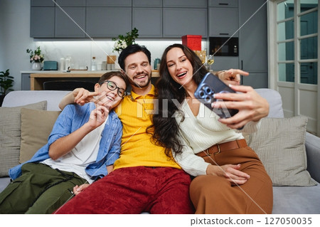 Family enjoying a playful moment together while taking a selfie indoors 127050035