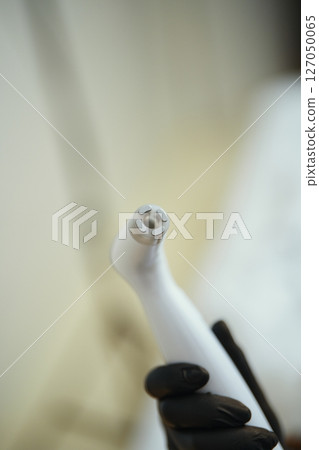 Portable dental cleaning tool held by gloved hand in clinic setting Portable dental cleaning tool held by gloved hand in clinic setting 127050065