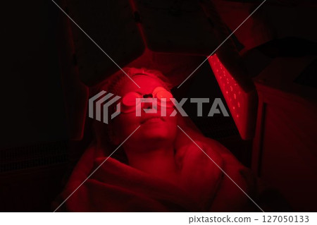 Woman receiving red light therapy treatment in wellness center 127050133