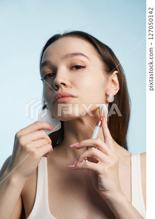Woman applying skincare treatment using beauty tools indoors 127050142