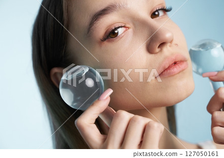 Young woman practicing facial therapy with cooling tools at home 127050161