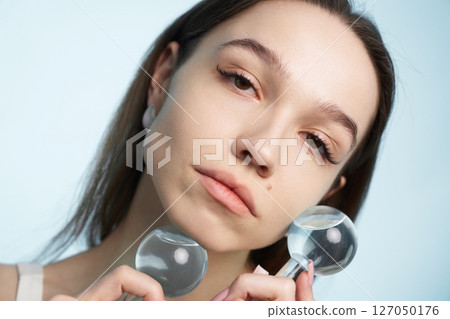 Woman holding glass globes for beauty treatment in studio setting 127050176