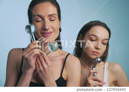 Women enjoying facial massage tools in a calm indoor environment 127050445