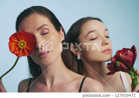 Two women express beauty with flowers in a studio setting 127050472