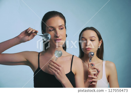 Models showcasing beauty products with magnifying glasses during a studio shoot 127050473