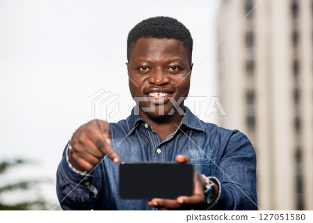 portrait of young african man with mobile phone, happy. 127051580