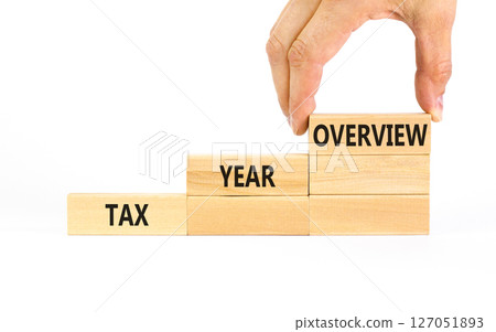 Tax year overview symbol. Concept words Tax year overview on beautiful wooden blocks. Beautiful white table white background. Businessman hand. Business tax year overview concept. Copy space. 127051893