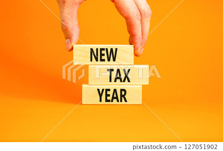 New tax year symbol. Concept words New tax year on beautiful wooden blocks. Beautiful orange background. Businessman hand. Business new tax year concept. Copy space. New tax year symbol. Concept words New tax year on beautiful wooden blocks. Beautiful orange background. Businessman hand. Business new tax year concept. Copy space. 127051902