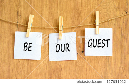 Be our guest symbol. Concept words Be our guest on beautiful white paper on wooden clothespin. Beautiful wooden background. Business and be our guest concept. Copy space. 127051912
