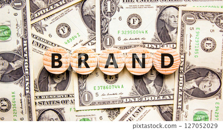 Brand symbol. Concept word Brand on beautiful wooden circles. Beautiful dollar bills. Beautiful background from dollar bills. Business brand concept. Copy space. 127052029