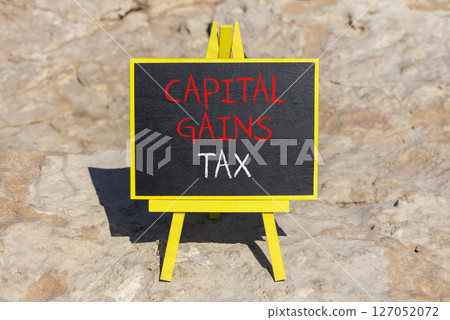 Capital gains tax symbol. Concept words Capital gains tax on beautiful blackboard. Beautiful brown stone beach background. Business and capital gains tax concept. Copy space. 127052072