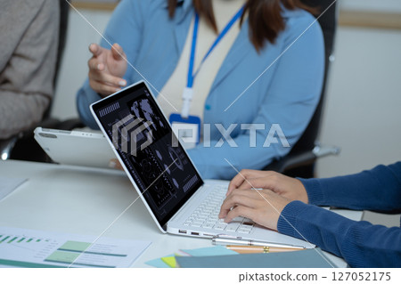 Business team doing paperwork, sitting at cafe on conference. Focused business team learning financial graphs, working on corporate project at briefing meeting. 127052175