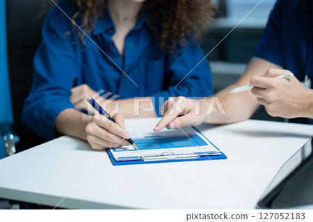 male doctor consulting woman patient filling form at consultation, talking to senior old patient filling signing medical paper at appointment visit in clinic. 127052183