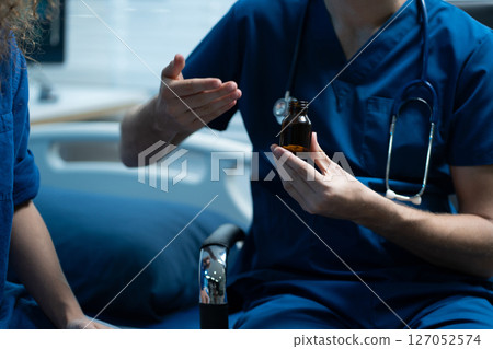 Therapist demonstrates the distribution of medication to the patient. 127052574