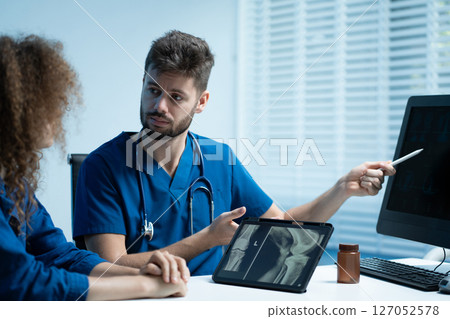 Knee model showing the process of osteoarthritis and knee arthroplasty, doctors explaining symptoms and treatment to patients. 127052578