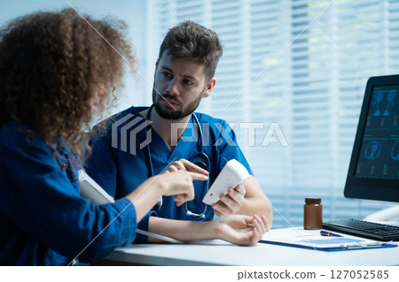 doctor checking woman blood pressure at clinic and filling patient history. 127052585