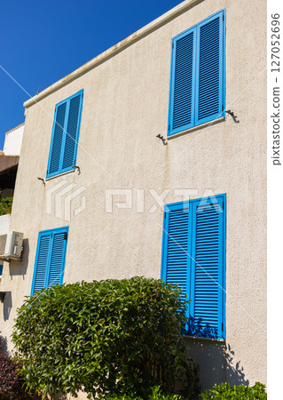 Facade with closed blue shutters. Mediterranean architecture, sunny climate, and summer lifestyle in coastal residential buildings 127052696