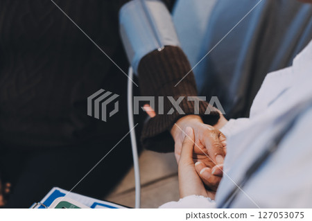 Doctor using Blood pressure monitor and stethoscope checking measuring arterial blood pressure on arm to a patient in the hospital, healthcare and medical concept 127053075
