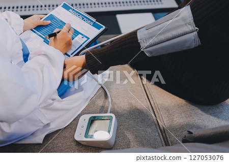 Doctor using Blood pressure monitor and stethoscope checking measuring arterial blood pressure on arm to a patient in the hospital, healthcare and medical concept Doctor using Blood pressure monitor and stethoscope checking measuring arterial blood pressure on arm to a patient in the hospital, healthcare and medical concept 127053076