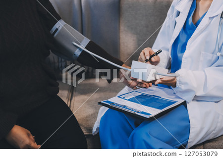 Doctor using Blood pressure monitor and stethoscope checking measuring arterial blood pressure on arm to a patient in the hospital, healthcare and medical concept 127053079