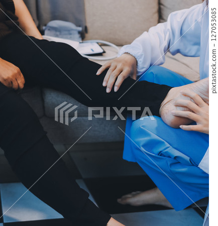 Young doctor examines senior patient's leg 127053085