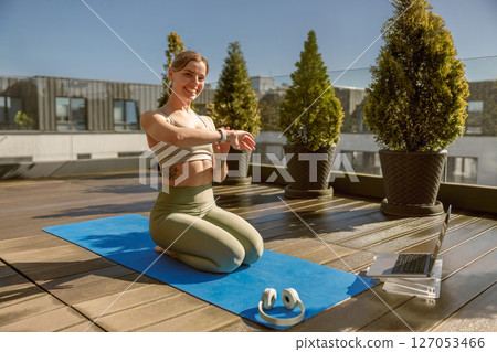 A woman is practicing yoga outdoors on a beautiful and sunny rooftop, embracing nature and serenity 127053466