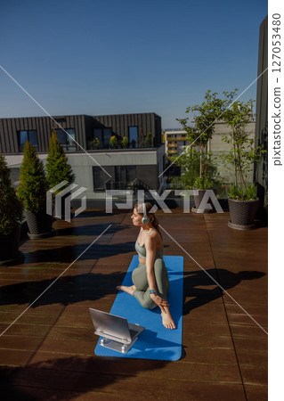 Engaging in an Outdoor Yoga Practice on a Rooftop, Enhanced with Digital Guidance and Tools Engaging in an Outdoor Yoga Practice on a Rooftop, Enhanced with Digital Guidance and Tools 127053480