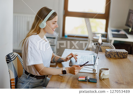A Focused Young Professional Works Remotely from Home on Their Laptop, Staying Productive 127053489