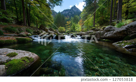 Scenic view of a clear river flowing through a forest with mountains in the background. 127053818
