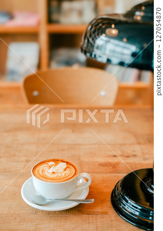 Latte art in a stylish cafe with a bookshelf in the background Latte art in a stylish cafe with a bookshelf in the background 127054870