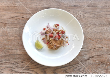 salty dry Indo-Pacific king mackerel fish topping chop shallot and chili with slice lemon salad on plate  127055325