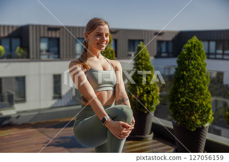 A woman practicing yoga on a rooftop, enjoying the city skyline and promoting health A woman practicing yoga on a rooftop, enjoying the city skyline and promoting health 127056159