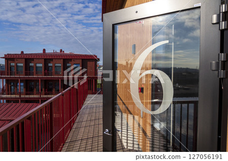 Number 6 on the glass door of an apartment building, sunny day 127056191