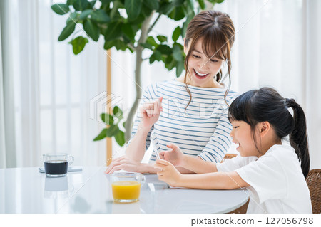 Parents and children looking at a tablet together in the living room Parents and children looking at a tablet together in the living room 127056798