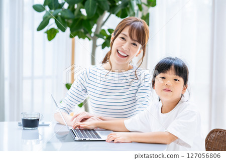 Parents and children looking at a tablet together in the living room Parents and children looking at a tablet together in the living room 127056806