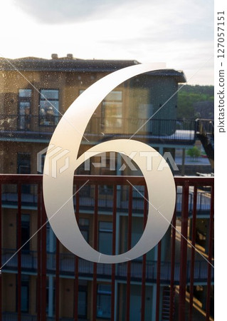 Number 6 on the glass door of an apartment building, sunny day 127057151