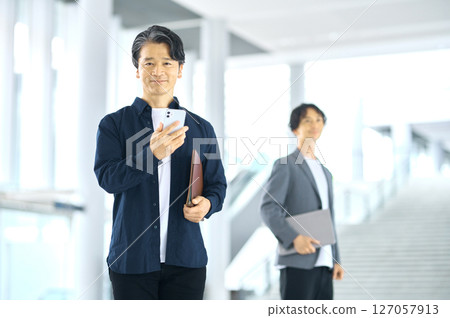 Middle businessman operating a smartphone Middle businessman operating a smartphone 127057913