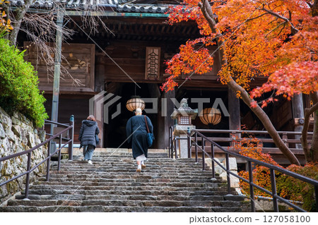 Buddhist priest walk on staircase to Hasedera temple in autumn, Nara 127058100