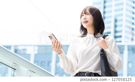 Woman/businesswoman holding a smartphone outdoors Woman/businesswoman holding a smartphone outdoors 127058125