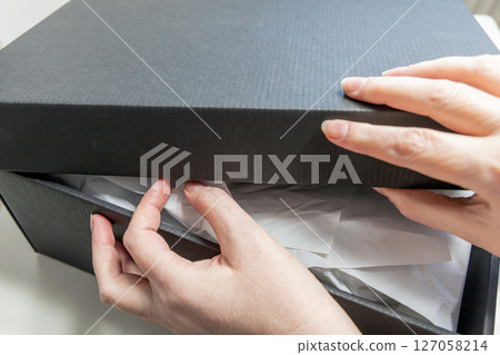 Women's hands unpack a delivered parcel or a gift 127058214
