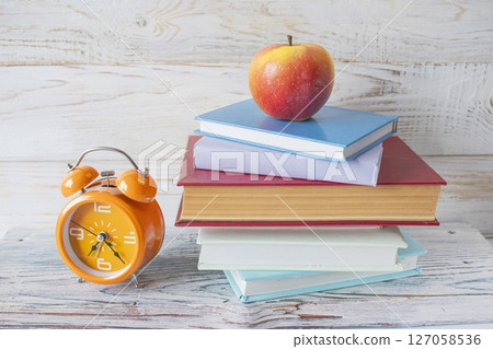 Alarm clock and stack of books on wooden background. Back to school concept. Alarm clock and stack of books on wooden background. Back to school concept. 127058536
