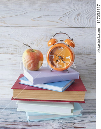 Alarm clock and stack of books on wooden background. Back to school concept. Alarm clock and stack of books on wooden background. Back to school concept. 127058537
