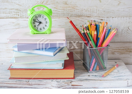 Alarm clock and stack of books on wooden background. Back to school concept. Alarm clock and stack of books on wooden background. Back to school concept. 127058539