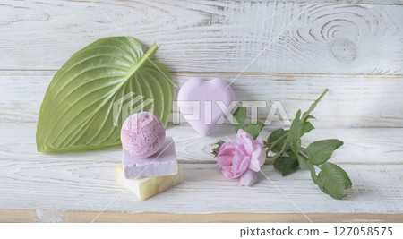 Spa still life with soap and pink rose flower on white wooden background. 127058575