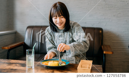 A young woman who eats at a cafe 127058786