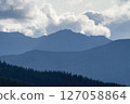 Majestic mountain peaks loom over a serene forest landscape 127058864