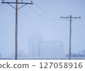 Grain elevator and power lines disappearing into the fog on a cold winter day 127058916