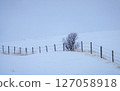 Wire fence running across snowy hills in winter 127058918
